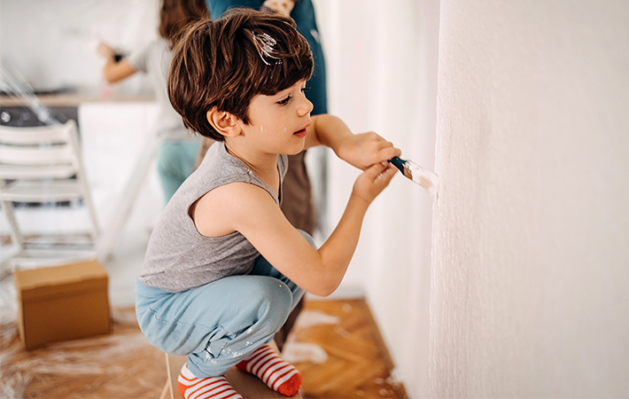 Little boy painting an interior wall