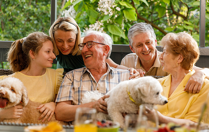 Happy multigenerational family smiles at one another while seating closely together
