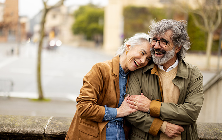Adult man and woman embrace while sharing a laugh.